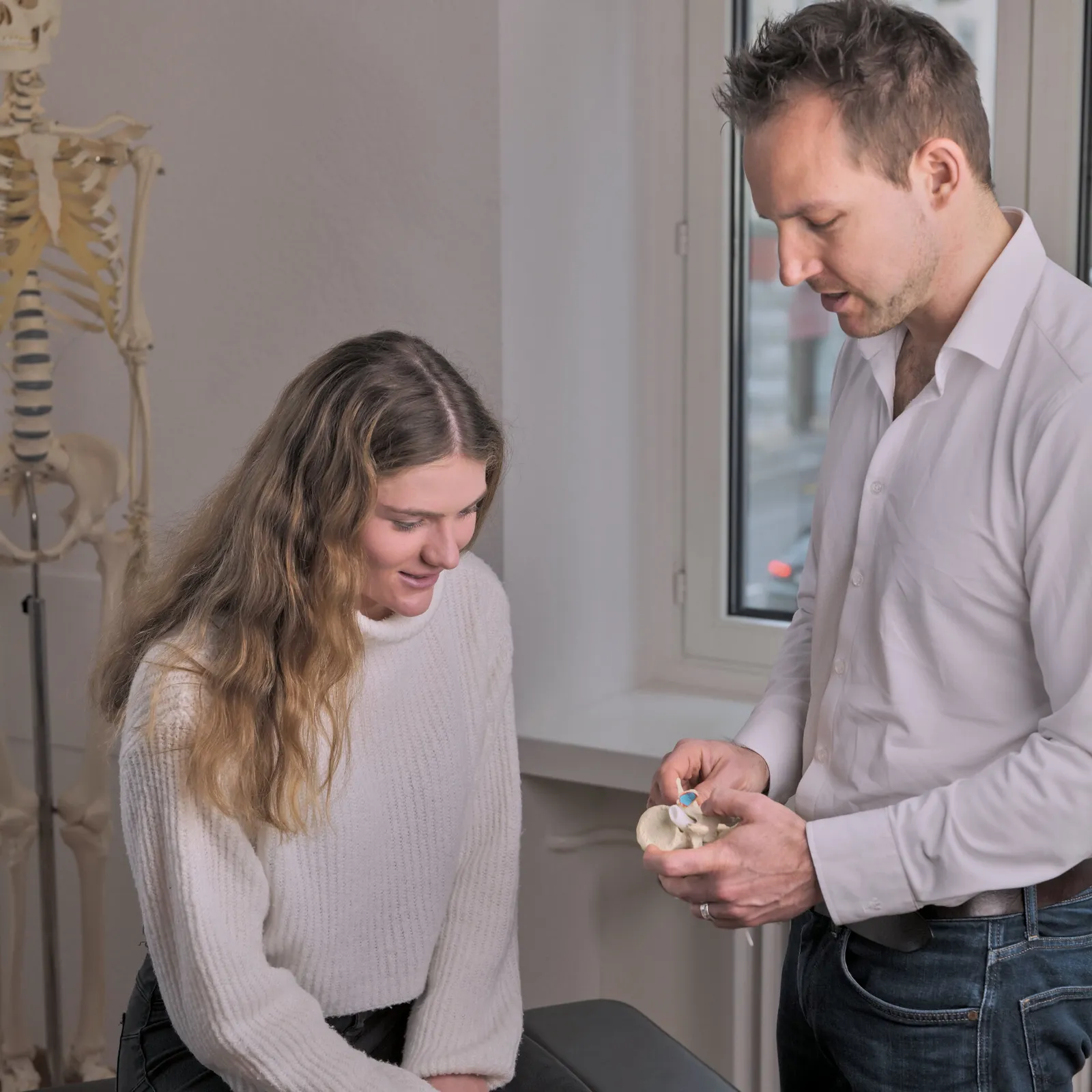 Dr. Florian Senn erklärt einer Patientin anhand eines Becken-Modells das McGill Assessment in der Chiropraktik-Praxis St. Gallen